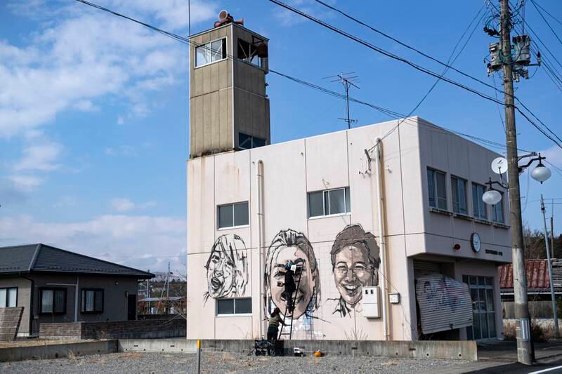 An artist creating a mural on an outer wall of the disused fire station in Futaba. NurPhoto via Getty Images