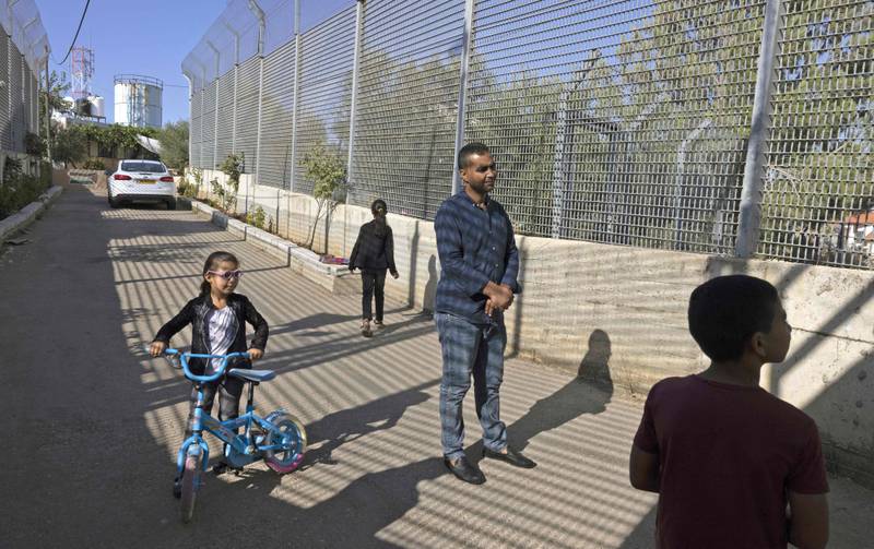 Palestinian Saadat Sabri Gharib, centre, walks with family members between Israeli army barriers that lead to his house.