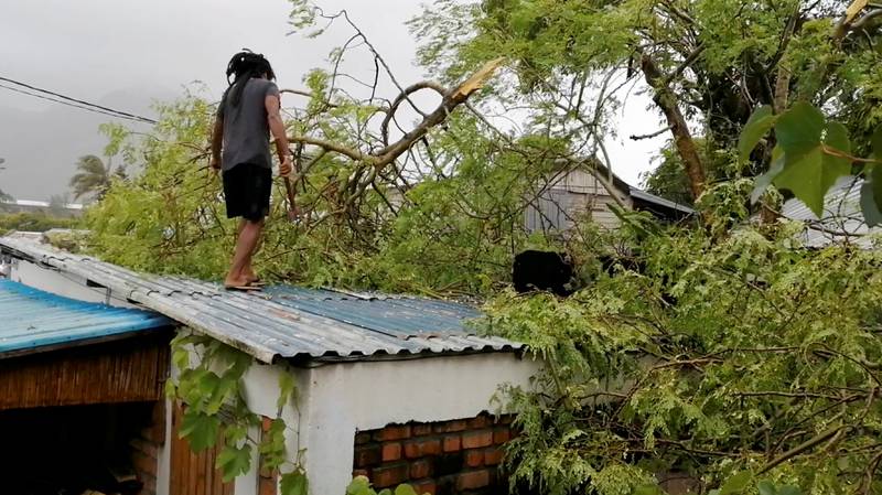 A man removes a fallen branch from the roof of a house during Cyclone Emnati in Fort Dauphin, Madagascar. Photo: of Louise du Plessis, Twitter @Louisedp3137 via Reuters