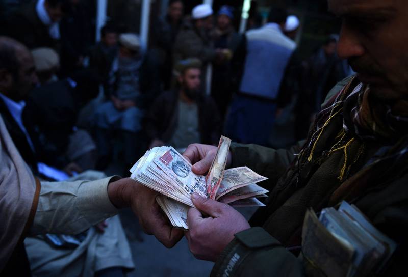 Afghan money changers count banknotes at the currency exchange Sarayee Shahzada market in Kabul. AFP