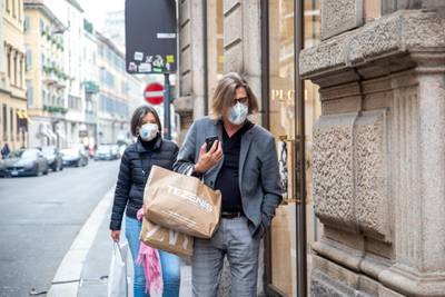 Pedestrians wearing protective face masks walk past shops in Milan, Italy.  Bloomberg