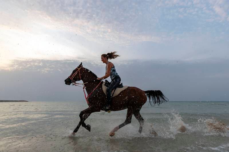 Owner of Arabian Star Stables, Rasha Hina, riding on the beach at sunset. 