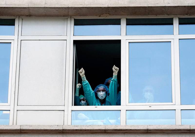 Medical staff from the Fundacion Jimenez Diaz Hospital gesture as neighbours applaud from their balconies in support of healthcare workers in Madrid, Spain. Reuters