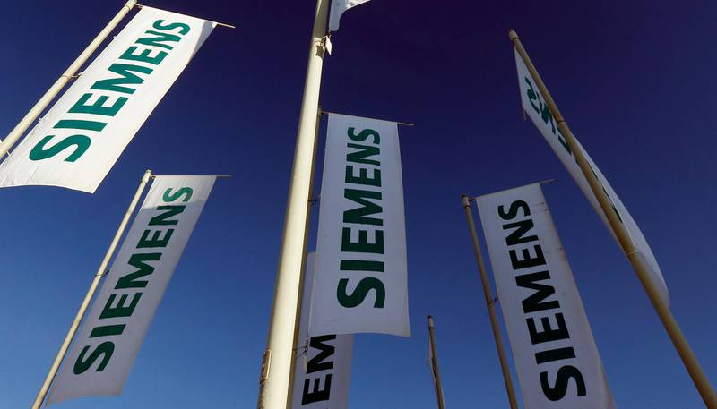 FILE - In this Jan. 23, 2013 file photo flags of German engineering conglomerate Siemens AG fly during an annual shareholder meeting in Munich, southern Germany. German industrial conglomerate Siemens AG says Friday, July 21, 2017 itâ€™s halting deliveries of power generation equipment to state-controlled companies in Russia and selling its stake in a Russian company that offers services for power plant control systems. (AP Photo/Matthias Schrader, File)