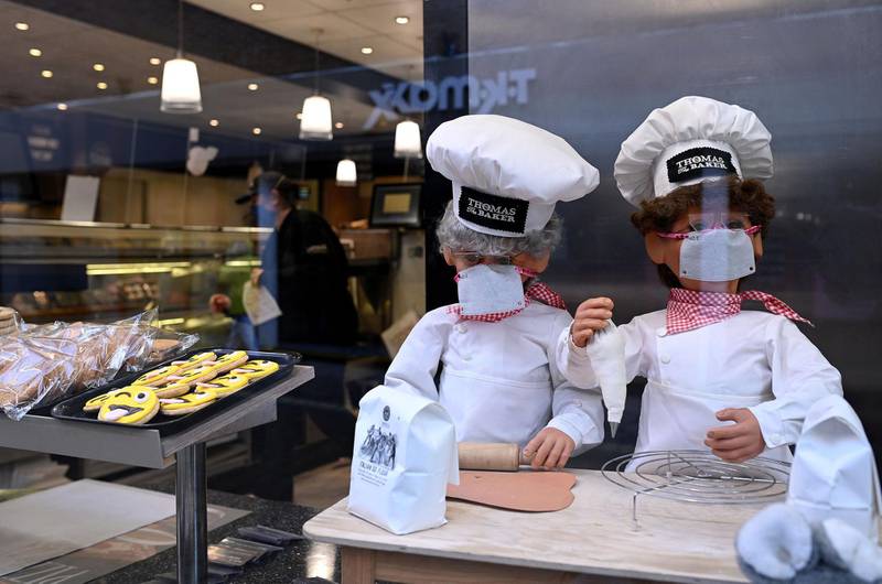 Puppets wearing face coverings are pictured in the window of a bakery, offering a take-away service in York. AFP