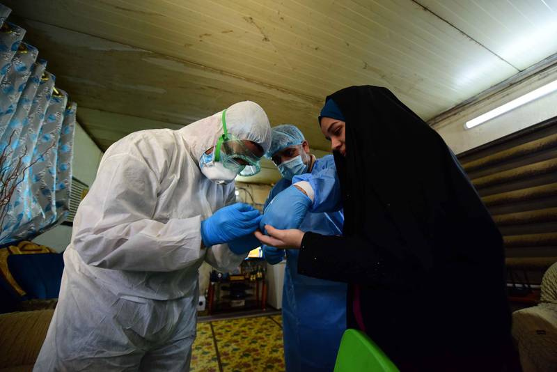 Medical specialists take a blood sample from a woman in Sadr City, Iraq.  EPA