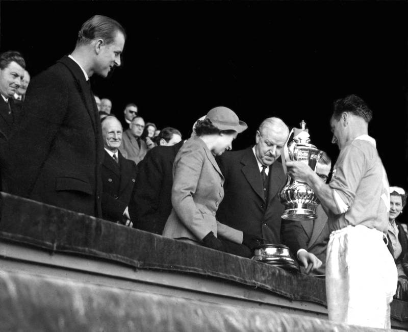 Blackpool captain Harry Johnston leading his team up to the Royal Box at Wembley Stadium to receive the FA Cup from Queen Elizabeth II after they beat Bolton Wanderers 4-3 in 1953. It was the first football match that the Queen had attended. PA