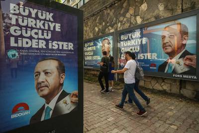In this photo taken on Saturday, June 9, 2018, people walk past election posters of Turkey's President Recep Tayyip Erdogan and his ruling Justice and Development (AKP) Party in Istanbul. The most powerful and polarizing leader in Turkish history is standing for re-election in a presidential vote on Sunday that could cement Turkey's switch from a parliamentary to a presidential system, which was narrowly approved in a referendum last year. (AP Photo/Emrah Gurel)
