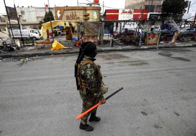 An Iraqi soldier stands guard next to the wreckage of protesters' tents at the protest site in Basra, southern Iraq.  EPA