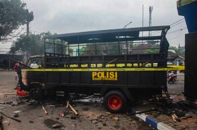 People walk past a torched police truck outside Kanjuruhan Stadium. EPA