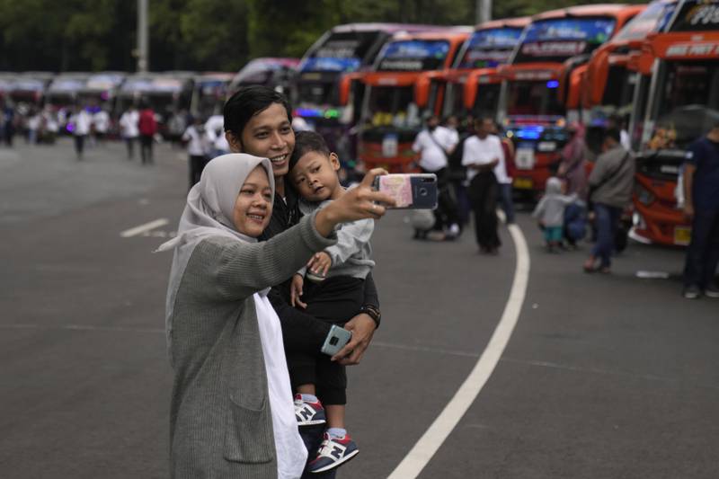 A family takes a selfie as they wait to board a free bus, sponsored by Indonesia's Ministry of State-Owned Enterprises, to their home village in Central Java. AP