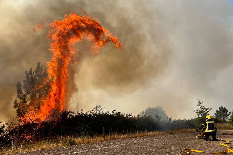 A forked tongue of flame flickers in the sky as firefighters tackle a wildfire in Pontevedra, Spain. EPA