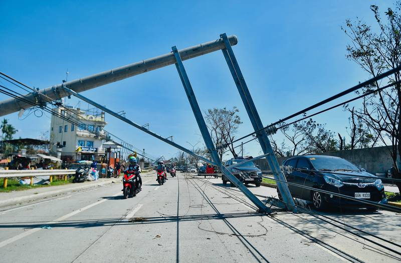 Motorists drive past an electricity pylon damaged by Typhoon Rai in Talisay, Cebu province, in the Philippines. AFP