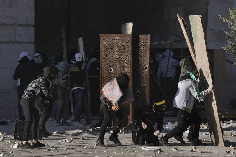 Palestinians use boards to protect themselves from Israeli police, who also used rubber bullets and stun grenades. AP
