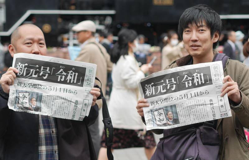 People hold up local papers reporting the announcement of the new era name "Reiwa" in Tokyo, April 1, 2019. AFP