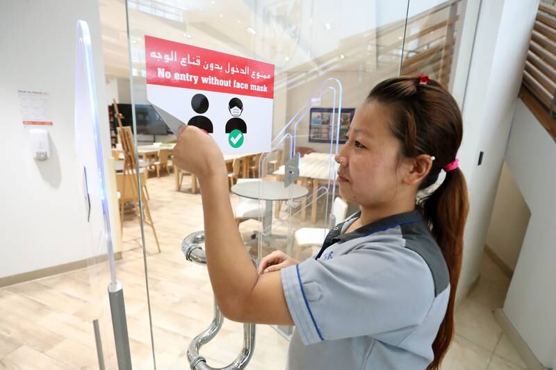 A member of staff takes down signage urging pupils to keep wearing masks at Brighton College in Dubai. Schools no longer require children and teachers to wear masks. All photos: Chris Whiteoak / The National