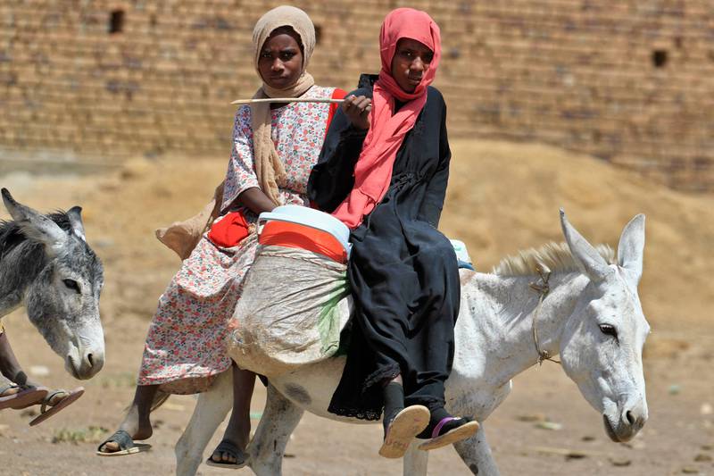Sudanese women ride their donkeys in the village.