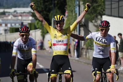 Tadej Pogacar of UAE Team Emirates wearing the overall leader's yellow jersey is flanked by teammates en route to victory at the Tour de France in Paris on Sunday, July 18, 2021.