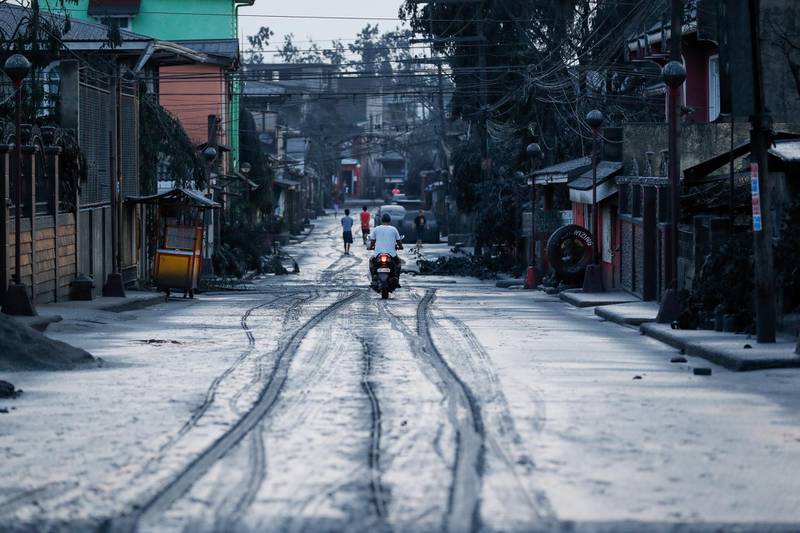 A motorcycle rider navigates through a muddy road after a volcano eruption in Talisay, Batangas. EPA