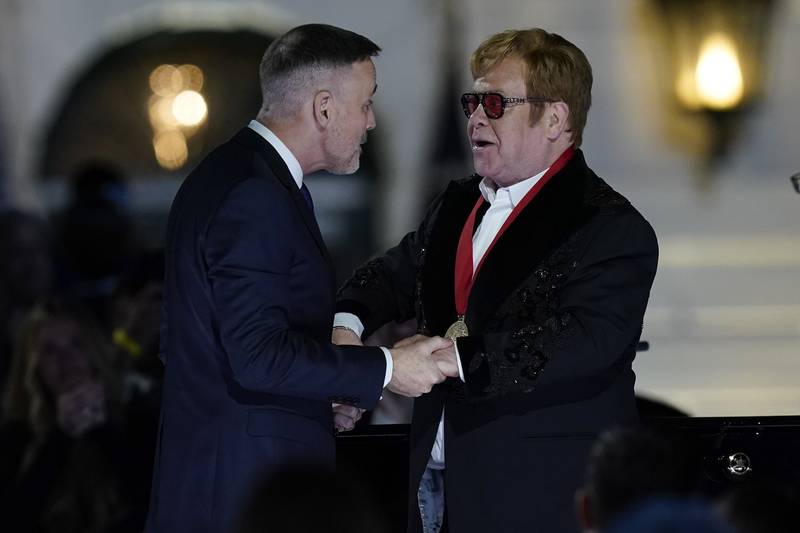David Furnish greets Sir Elton, his partner, after President Biden presented the award. AP
