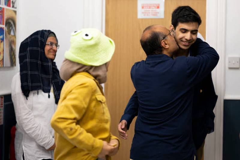 Sarim Rafique receives a kiss from his father as his mother and sister look on, after he received his results at Ffynone House School in Swansea, Wales. Getty Images