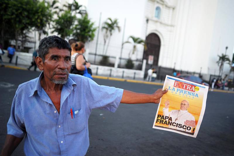 A man sells an extra edition of a newspaper with the announcement of the election of Argentina's cardinal Jorge Mario Bergoglio as the new Pope Francis I on March 13, 2013 in downtown San Salvador. Argentina's Jorge Mario Bergoglio was elected Pope Francis I on Wednesday, becoming the church's first Latin American pontiff after a conclave to elect a leader of the world's 1.2 billion Catholics. AFP PHOTO/ Jose CABEZAS (Photo by Jose CABEZAS / AFP)
