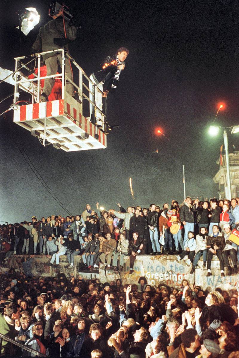 American singer and actor David Hasselhoff hovers in the cage of a hoisting crane above the celebrating people on Berlin Wall and sings "Looking for Freedom" during the first German-German New Year's Eve party on the 31st of December in 1989 at Brandenburg Gate. (Photo by WÃ¶stmann/picture alliance via Getty Images)