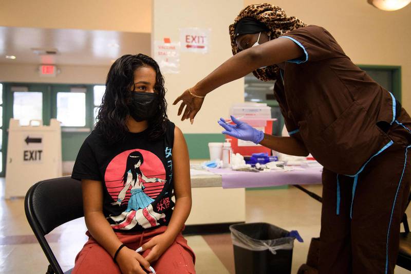 Brianna Banuelos (L), 12, receives a first dose of the Pfizer Covid-19 vaccine after it was approved for use by the FDA in children 12 and over at a Los Angeles County mobile vaccination clinic on May 14, 2021 in Los Angeles, California. / AFP / Patrick T. FALLON
