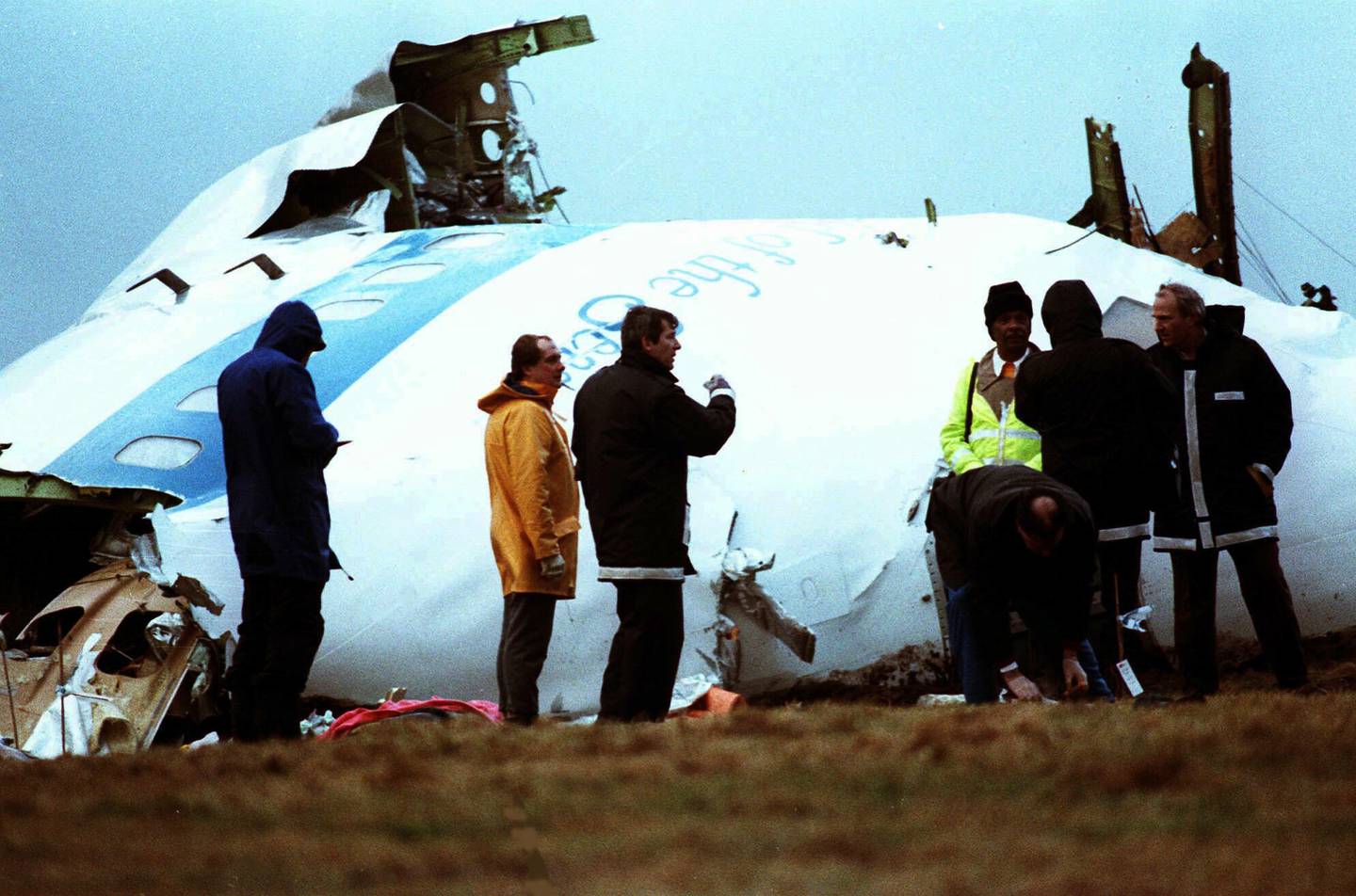 Unidentified crash investigators inspect the nose section of the crashed Pan Am flight 103, a Boeing 747 airliner in a field near Lockerbie, Scotland, Dec.  23, 1988. AP
