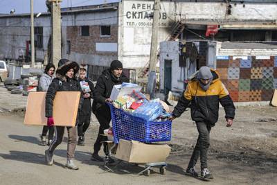 Residents carry water from a food warehouse, which is under the control of the breakaway Donetsk People's Republic, on the outskirts of Mariupol. AP