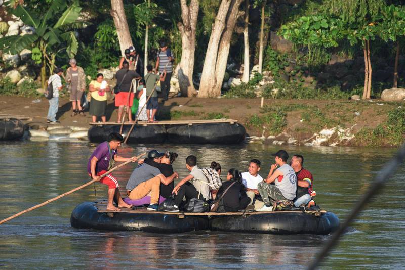 Honduran migrants taking part in a caravan heading to the US, cross the Suchiate River, natural border between Guatemala and Mexico, in makeshift rafts, in Ciudad Tecun Uman, Guatemala, on October 21, 2018. Thousands of Honduran migrants resumed their march toward the United States on Sunday from Guatemalan Ciudad Tecun Uman heading to Tapachula, Mexico, AFP journalists at the scene said. / AFP / ORLANDO SIERRA
