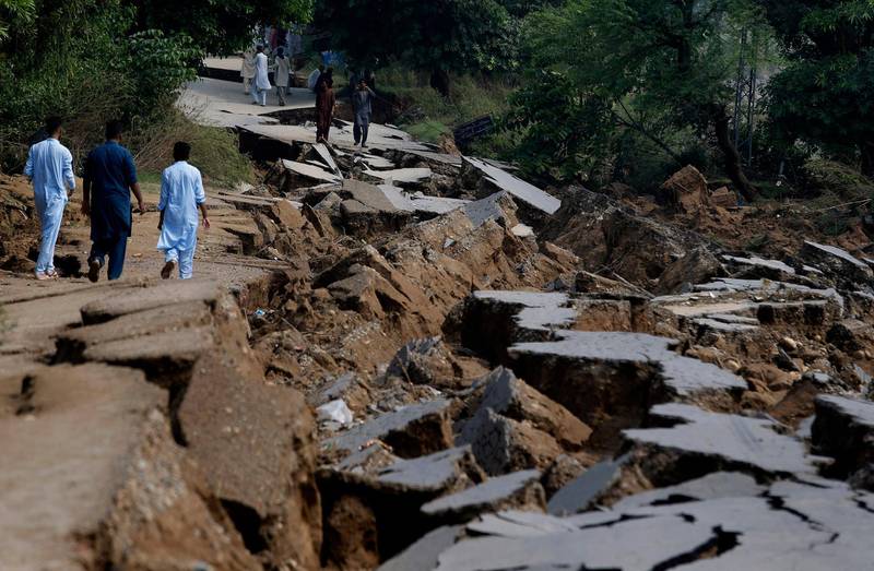 Residents walk alongside a damaged portion of a road caused by a powerful earthquake in Jatlan near Mirpur, in northeast Pakistan, Wednesday, Sept. 25, 2019. Thousands of people whose homes were damaged because of a strong earthquake are desperately waiting for the arrival of government help, 22 hours after the 5.8 magnitude tremor struck Pakistan-held Kashmir and elsewhere, killing 25 people and injuring 700. (AP Photo/Anjum Naveed)
