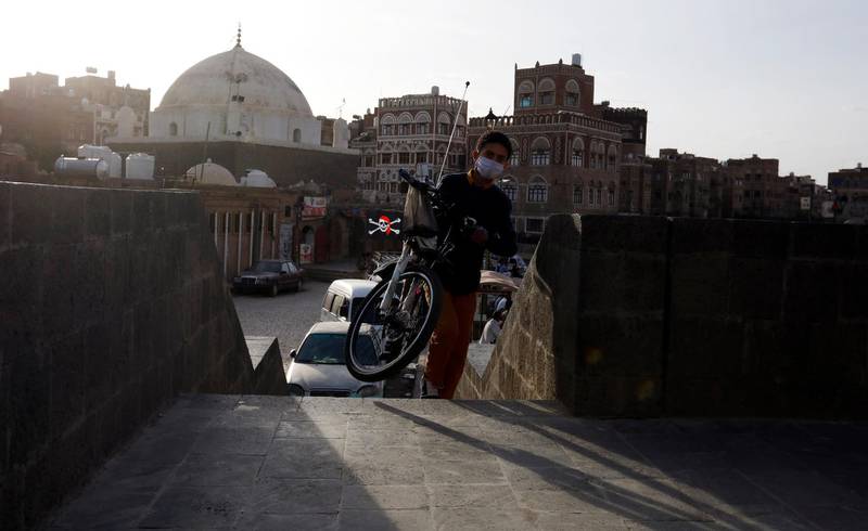 A Yemeni child wearing a protective face mask carries a bicycle on to a pedestrian bridge amid the ongoing coronavirus pandemic in Sanaa.  EPA