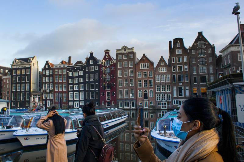 A woman takes images of empty and moored canal cruise boats docked in Amsterdam, Netherlands. AP Photo