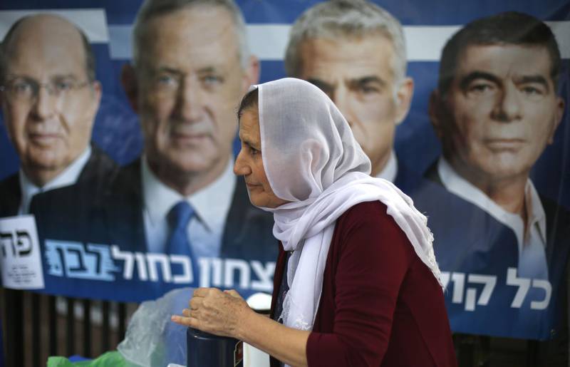 An Israeli arab woman serves beverages in front of an electoral poster at a poling station during Israel's parliamentary elections. AFP