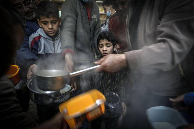 A boy waits as Palestinian Walid Al Hattab, right, distributes soup to people in need during Ramadan in Gaza city. AFP