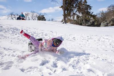 Mia Donjuan, 4, falls off her sledge as she slides down a hill in the Elmwood district of Dallas. AP
