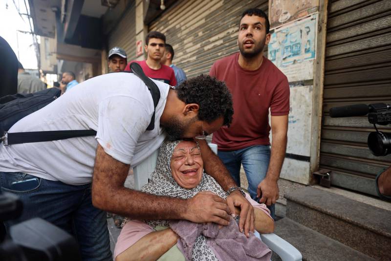 A relative comforts an injured Palestinian woman in Gaza city following an Israeli air strike. AFP

