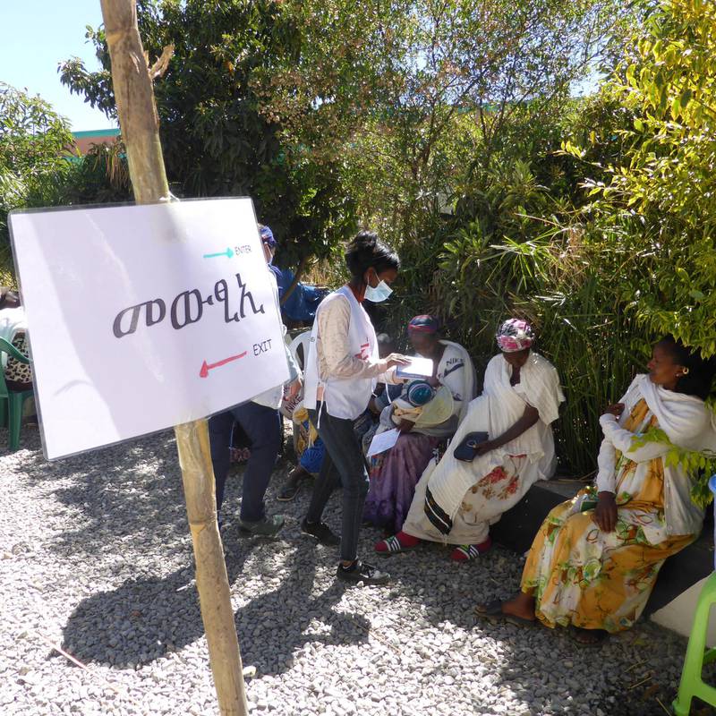 An MSF translator talks with patients waiting for triage during a mobile clinic in Hawzen, northeast Tigray.