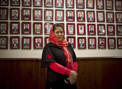 Fawzia Koofi, a government peace negotiator and former member of parliament, stands before a wall with photos of Afghan MPs. AP Photo