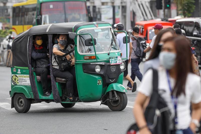 People ride a three wheeled motorcycle despite the 'social distancing' measures in Makati, Philippines.  EPA