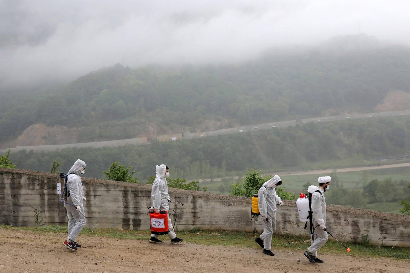 Volunteers wearing protective clothing, take part in disinfecting a village during the coronavirus outbreak, in the outskirts of the city of Ghaemshahr, in north of Iran, Wednesday, April 29, 2020. (AP Photo/Ebrahim Noroozi)