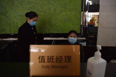 Staff members wearing facemasks to help protect against the SARS-like virus spreading affecting the city are pictured in the lobby of their hotel, in the city of Wuhan in Hubei province. AFP