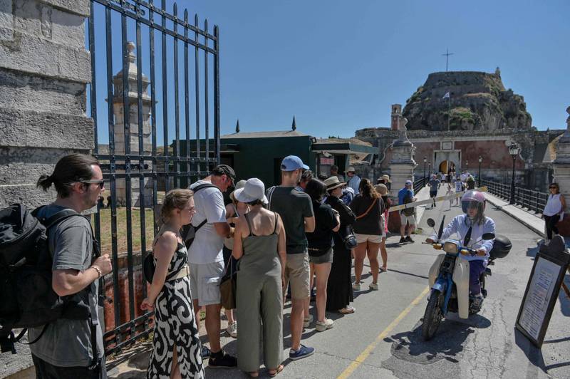 Tourists wait in line to take a tour of the clock tower at the Old Fortress on the Greek island of Corfu, during a heatwave, in July. AFP
