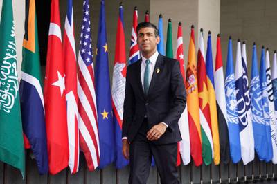 British Prime Minister Rishi Sunak walks past the flags of assembled nations. AFP