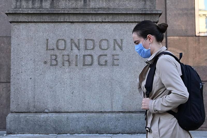 A commuter walks across London Bridge toward the City of London. AFP