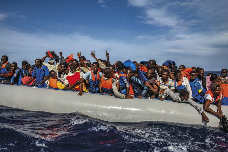 More than 100 African migrants from Gambia, Mali, Senegal, Ivory Coast, Guinea and Nigeria wait to be rescued by the Italian Navy from a dinghy, in the Mediterranean between Italy and Libya, in October 2014.