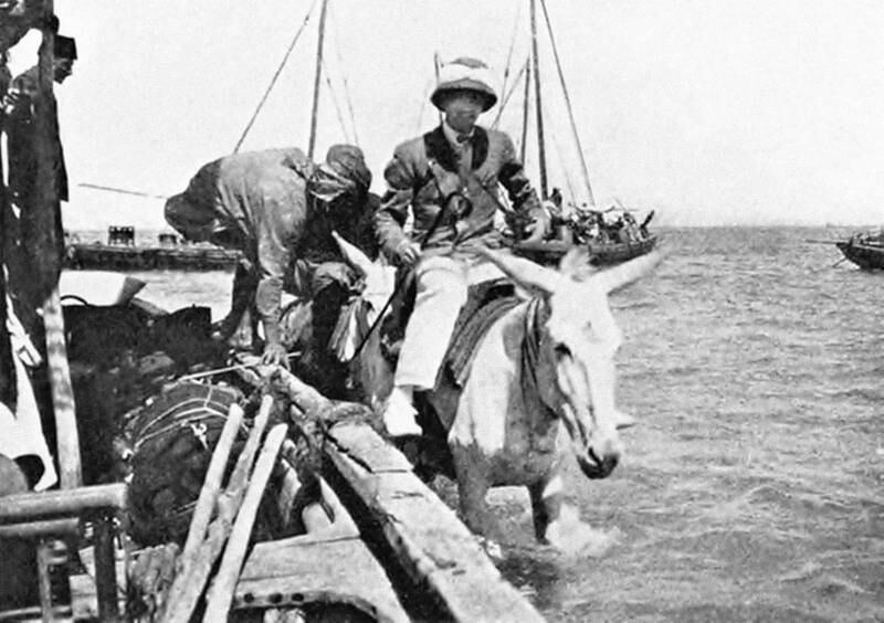 Jacques Cartier on a donkey in Bahrain. In the background can be seen a sailing ship. Photo: Francesca Cartier Brickell