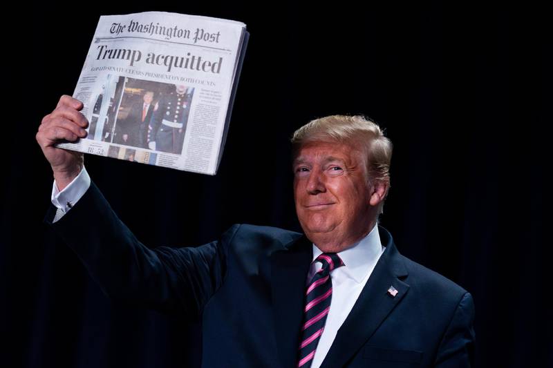 President Donald Trump holds up a newspaper during the 68th annual National Prayer Breakfast, at the Washington Hilton, Thursday, Feb. 6, 2020, in Washington. (AP Photo/ Evan Vucci)