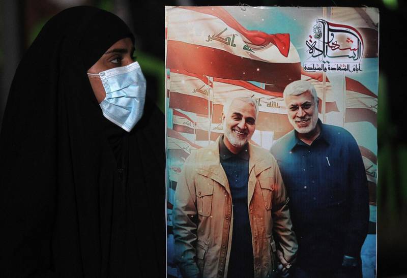 An Iraqi woman carries a portrait of Qassem Suleimani and Abu Mahdi Al Muhandis. AFP